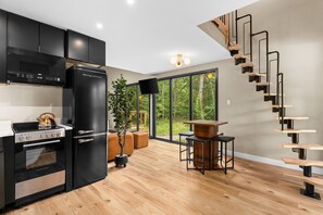 A modern kitchen with black cabinetry, a black refrigerator, and a wooden stove.