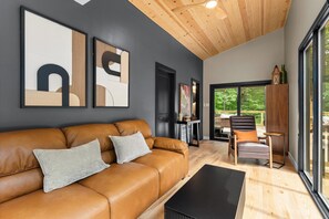 Ein modernes Wohnzimmer mit einer Ledersofa, einem schwarzen Couchtisch und Kunstwerken an den Wänden.