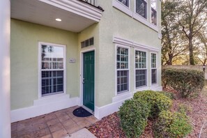 A two-story building with a green door, numbered 1102, and a small porch with a tiled floor. - *TWO* Sparkling Pools, Gated Condo, Walk to the Beach! (Gulfport)