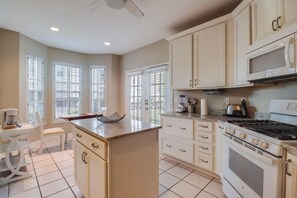 A kitchen with a central island, white cabinetry, and a stove. - *TWO* Sparkling Pools, Gated Condo, Walk to the Beach! (Gulfport)