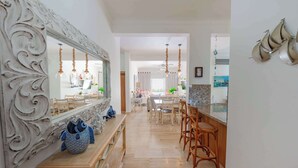 Un vaste espace dédié à la salle à manger, agrémenté d’un grand miroir, de meubles en bois et de luminaires suspendus.