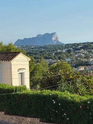 Ein Gebäude mit Ziegeldach, Steinwand und Blick auf eine gebirgige Landschaft.