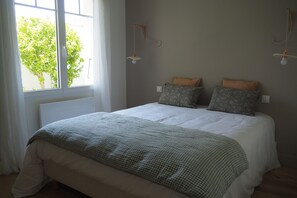 Ein Schlafzimmer mit einem großen Bett, einem Fenster mit Vorhängen und zwei Wandleuchten.