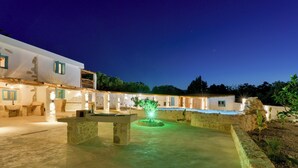 A courtyard with a fountain, stone benches, and a building with blue shutters. - Aspasia Wabi Retreat by CVR (Roustika)