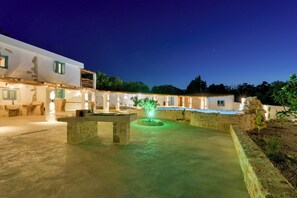 A courtyard with a fountain, stone benches, and a building with blue shutters. - Aspasia Wabi Retreat by CVR (Roustika)