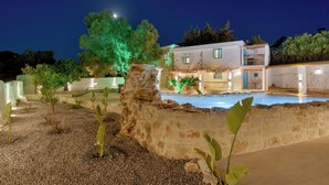 A two-story building with a swimming pool, stone walls, and green plants. - Aspasia Wabi Retreat by CVR (Roustika)