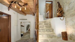 A stone staircase with a wooden handrail, a rustic ceiling with exposed beams, and a wooden door. - Aspasia Wabi Retreat by CVR (Roustika)