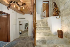 A stone staircase with a wooden handrail, a rustic ceiling with exposed beams, and a wooden door. - Aspasia Wabi Retreat by CVR (Roustika)