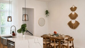 Eine moderne Küche mit einer Marmorinsel, einem Holzespeisetisch und Stühlen.
