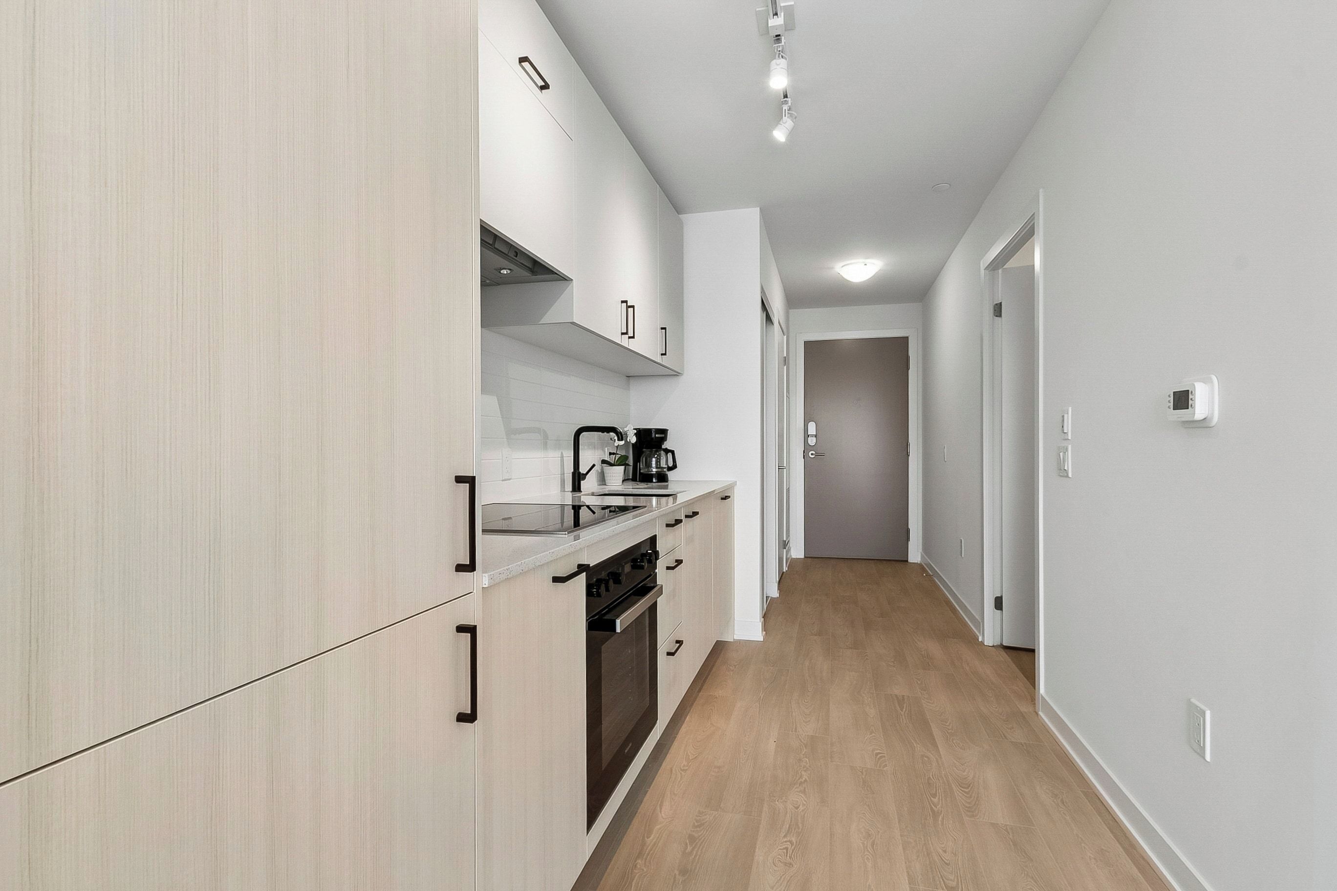 A modern kitchen with white cabinetry, a built-in oven, and a coffee maker.