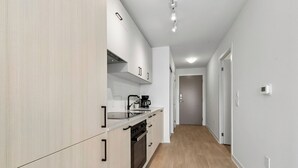 A modern kitchen with white cabinetry, a built-in oven, and a coffee maker. - Stylish 2bed2bath| Parking | Gym | Sauna|4ppl (Toronto)