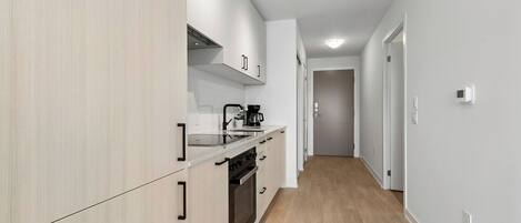 A modern kitchen with white cabinetry, a built-in oven, and a coffee maker.