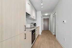 A modern kitchen with white cabinetry, a built-in oven, and a coffee maker.