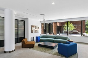 Ein modernes Interieur mit einer Eckcouch, einem Couchtisch und einem großen Fenster mit Blick ins Freie.
