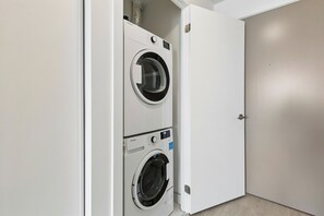 A laundry room with two stacked washing machines and a closed door.