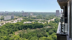 A high-rise building with a view of a cityscape and surrounding greenery. - Stylish 2bed2bath| Parking | Gym | Sauna|4ppl (Toronto)