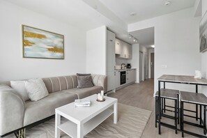 A modern living room with a sofa, a coffee table, and a dining area with stools.