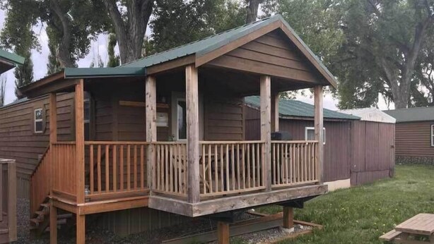Une cabane en bois avec une véranda, un petit escalier et une cour clôturée.