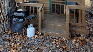 Une petite cabane en bois avec une pancarte indiquant « SMALL FRY 1 », un barbecue et une bouteille de propane.