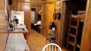 Une cuisine compacte équipée d’un évier, d’une cuisinière et d’un petit coin repas avec une table et une chaise.