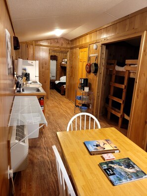 A compact kitchen with a sink, stove, and a small dining area with a table and chair.