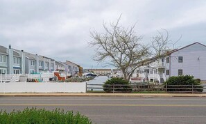 A waterfront residential area with houses, a dock, and a tree. - 2-bedroom Condo with a Relaxing Pool and Walking Distance to the Beach/Boardwalk (Ocean City)