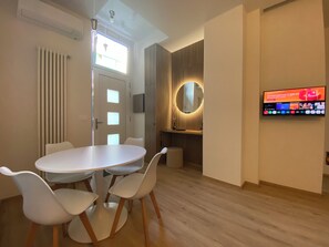 A modern interior with a round mirror, a flat-screen TV, and a white dining table with chairs. - Madama Apartment, new one-bedroom apartment, private parking, metro-city center. (Torino)