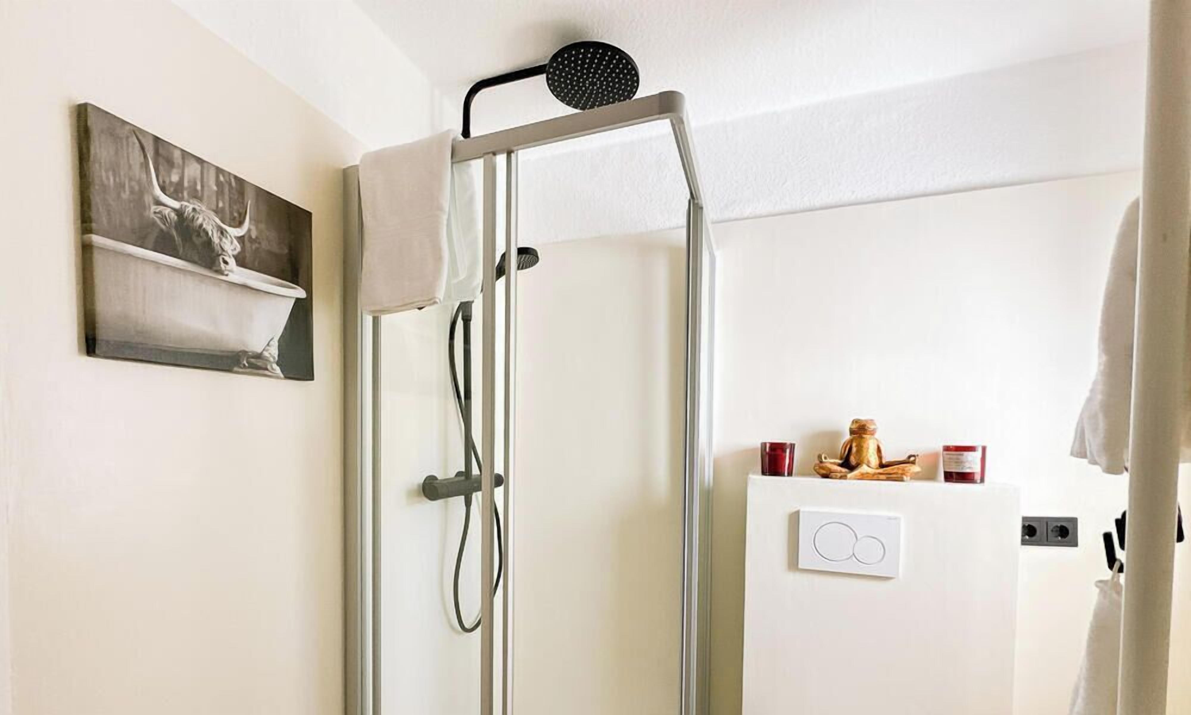 Eine Dusche mit Duschbrause, Handtuchhalter und einer fest montierten Bedienpanel.