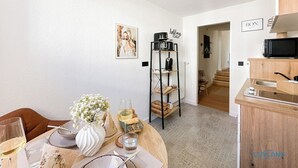 A dining area with a table set for two, a coffee machine, and a shelf with kitchen items. - Vacation apartment Alte Liebe & Meer (Cuxhaven)