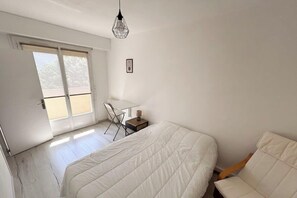 A bedroom with a bed, a desk, and a chair. - Bright apartment in the city center with balcony (La Roche-sur-Yon)