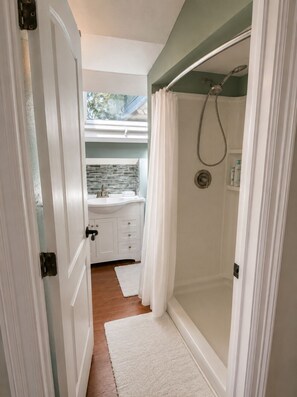 Un baño con ducha, lavamanos y ventana.