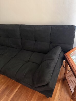 Un sofá negro con una mesita de madera.