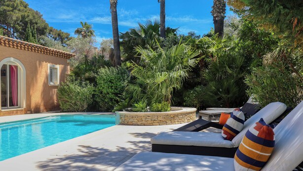 A poolside area with lounge chairs and a stone planter.