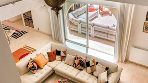 A living room with a sectional sofa, a coffee table, and a view through a glass door to an outdoor seating area.