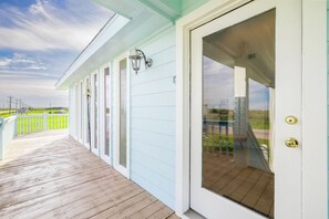 A covered porch with a wooden deck, a white door with a glass panel, and a metal lantern.