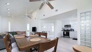 A spacious living area with a wooden dining table, chairs, a sofa, and a ceiling fan. - The Seashell Suite Cozy 1BR Near the Beach (Bolivar Peninsula)