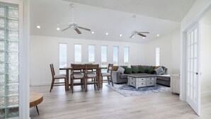 A spacious living area with a dining table, chairs, a sofa, and ceiling fans. - The Seashell Suite Cozy 1BR Near the Beach (Bolivar Peninsula)