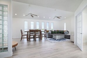 A spacious living area with a dining table, chairs, a sofa, and ceiling fans.