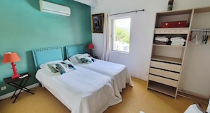 Une chambre d’hôtel avec deux lits, une lampe rouge, une armoire et une fenêtre donnant sur un beau paysage.