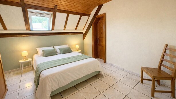 A bedroom with a bed, bedside lamps, a chair, and a wooden ceiling. - Large house with garden and terrace in Lapoutroie (Lapoutroie)