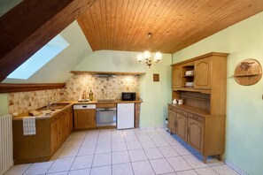 Cucina con mobili in legno, lavastoviglie, forno a microonde e ventilatore a soffitto.