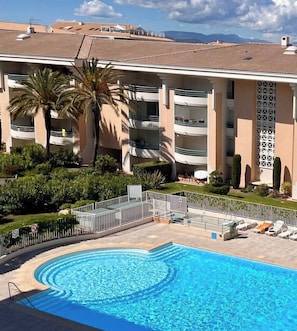 Un hotel con piscina, palmeras y vistas a las montañas.