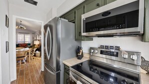 A modern kitchen with stainless steel appliances, a dining area with wicker furniture, and a visible kitchen island. - World Cup • Stay 15 Min to Stadium • Private Yard (Arlington)