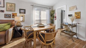 A living room with a sofa, a dining table with chairs, a lamp, and framed pictures on the walls. - World Cup • Stay 15 Min to Stadium • Private Yard (Arlington)