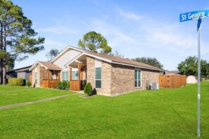 Een gelijkvloers huis met een bakstenen gevel, een voortuin en een verzorgd gazon.
