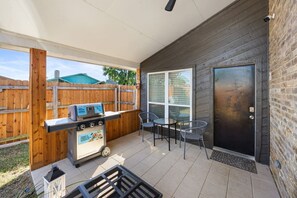 Une terrasse extérieure équipée d’un barbecue, d’une porte et d’une fenêtre.
