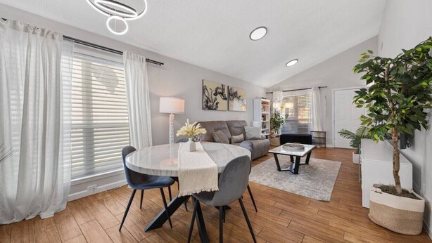 Ein modernes Wohnzimmer mit Esstisch, Sofa und einer Zimmerpflanze.