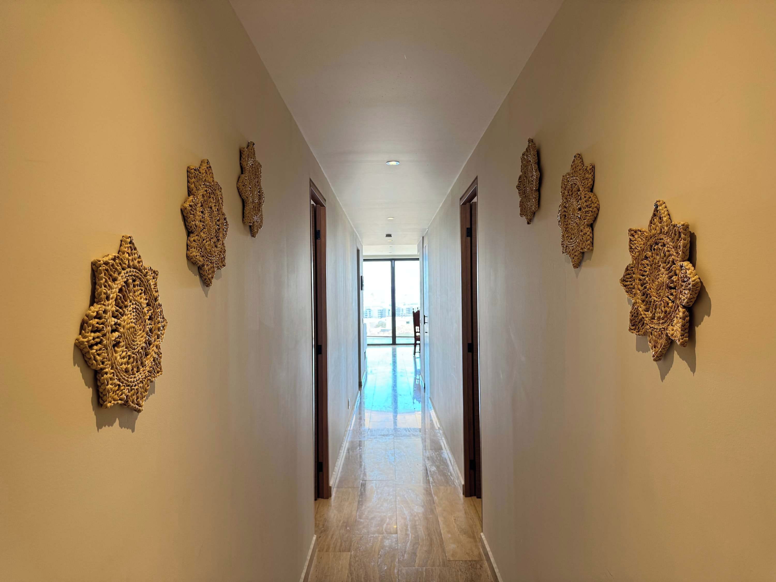 A hallway with patterned wall decorations and a view to a swimming pool.
