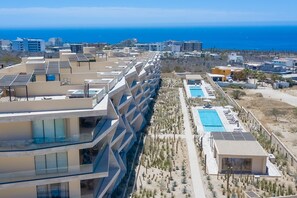 A modern hotel with multiple balconies, a swimming pool, and a view of the ocean. - Charming Coastal Resort With Ocean Views, Pool, Gym and Shared Amenities (Cabo San Lucas)