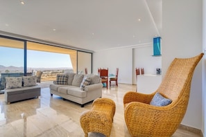 Ein modernes Wohnzimmer mit einer Couch, Sesseln und Blick auf die Stadt.